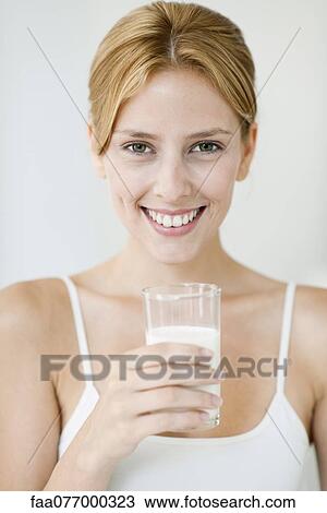 Stock Image - Young woman holding glass of milk, portrait. Fotosearch