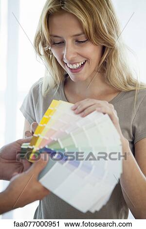 Stock Image - Young woman looking at paint swatches. Fotosearch