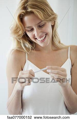 Young woman looking at pregnancy test, smiling View Large Photo Image Stock Image - Young woman looking at pregnancy test, smiling. Fotosearch