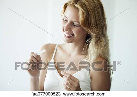 Young woman looking at pregnancy test, smiling View Large Photo Image Stock Image - Young woman looking at pregnancy test, smiling. Fotosearch