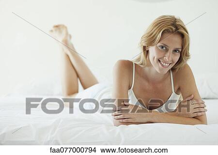 Young woman lying on bed View Large Photo Image Picture - Young woman lying on bed. Fotosearch