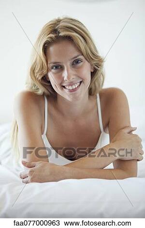 Young woman lying on bed View Large Photo Image Stock Image - Young woman lying on bed. Fotosearch