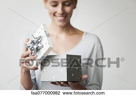 Stock Image - Young woman opening gift box. Fotosearch