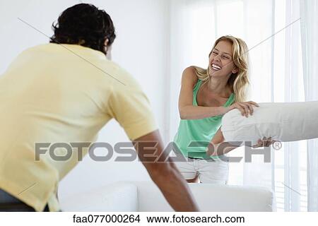 Young woman pillow fighting husband View Large Photo Image Picture - Young woman pillow fighting husband. Fotosearch