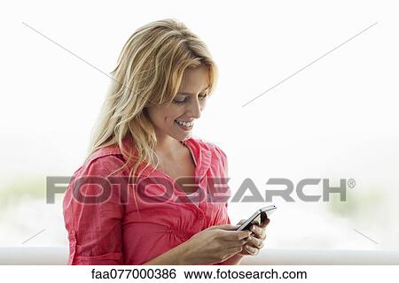 Stock Photograph - Young woman text messaging on cell phone. Fotosearch