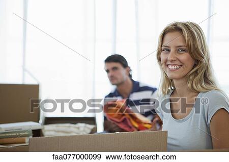 Stock Photo - Young woman unpacking in new house. Fotosearch