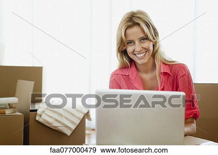 Young woman using laptop computer in new house with cardboard boxes View Large Photo Image Stock Photo - Young woman using laptop computer in new house with cardboard boxes. Fotosearch