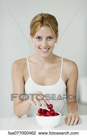 Stock Image - Young woman with bowl of strawberries. Fotosearch