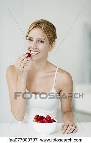 Stock Photo - Young woman with bowl of strawberries, portrait. Fotosearch