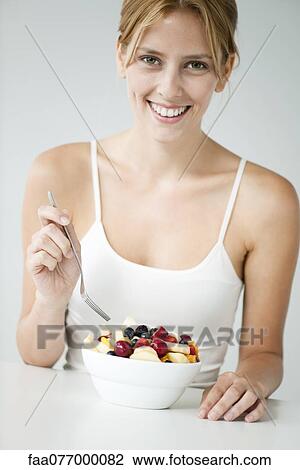 Stock Image - Young woman with fruit bowl. Fotosearch