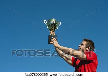 Stock Photography - Athlete holding up trophy. Fotosearch