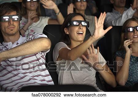 Stock Image - Audience enjoying 3-D movie in theater. Fotosearch