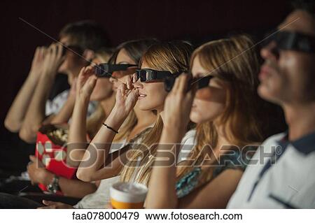Stock Photo - Audience in move theater putting on 3-D glasses. Fotosearch