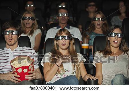 Stock Image - Audience wearing 3-D glasses in movie theater. Fotosearch