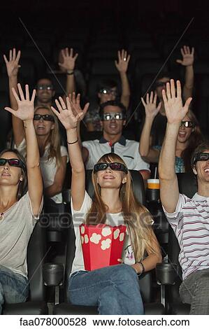 Audience wearing 3-D glasses in movie theater, arms reaching up View Large Photo Image Stock Photo - Audience wearing 3-D glasses in movie theater, arms reaching up. Fotosearch