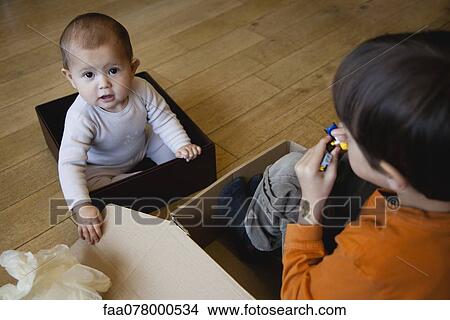Boy and baby sister playing in cardboard boxes View Large Photo Image Picture - Boy and baby sister playing in cardboard boxes. Fotosearch