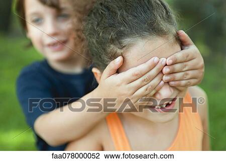 Stock Image - Boy covering girl's eyes. Fotosearch