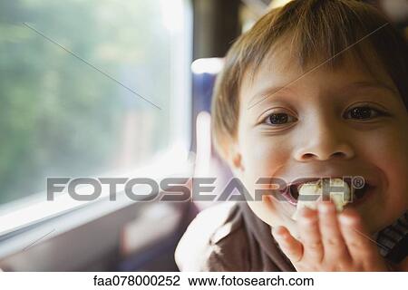 Stock Image - Boy eating chips, portrait. Fotosearch