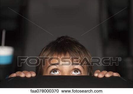 Boy peeking over top of seat during horror movie in theater View Large Photo Image Stock Image - Boy peeking over top of seat during horror movie in theater. Fotosearch