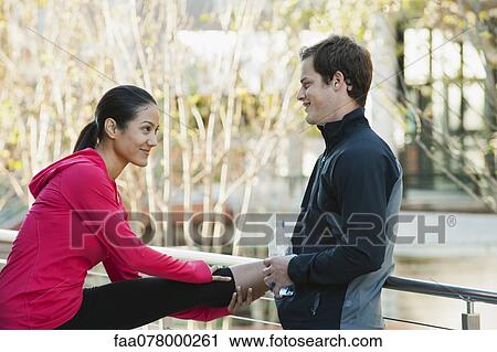 Boyfriend standing by girlfriend stretching on railings View Large Photo Image Stock Image - Boyfriend standing by girlfriend stretching on railings. Fotosearch
