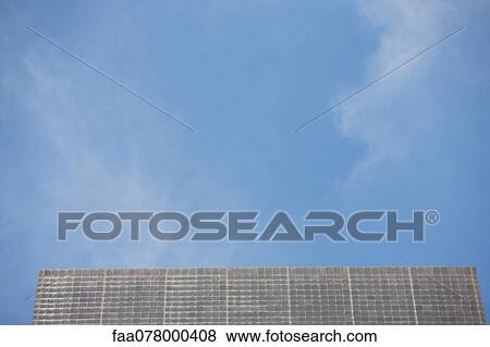 Stock Photo - Building facade and blue sky, low angle view. Fotosearch
