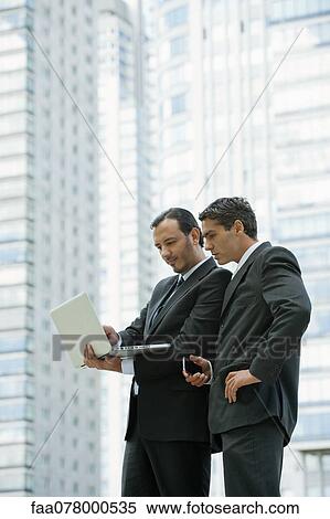 Stock Photography - Business associates using laptop computer outdoors. Fotosearch