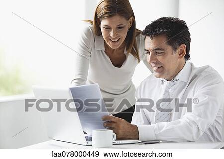 Stock Photo - Business colleagues looking at laptop computer together. Fotosearch