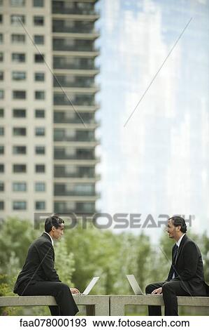 Business executives discussing work while using laptop computers outdoors View Large Photo Image Stock Image - Business executives discussing work while using laptop computers outdoors. Fotosearch
