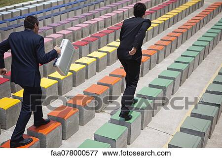 Stock Photo - Business executives racing on bleachers, rear view. Fotosearch