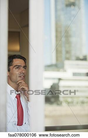 Businessman in office, seen from outside of window View Large Photo Image Stock Photograph - Businessman in office, seen from outside of window. Fotosearch