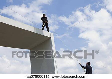 Stock Photography - Businessman lends helping hand to colleague. Fotosearch