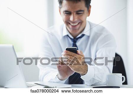 Picture - Businessman using smartphone, smiling. Fotosearch