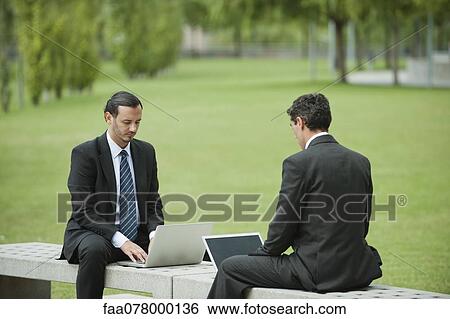 Stock Photograph - Businessmen using laptop computers outdoors. Fotosearch