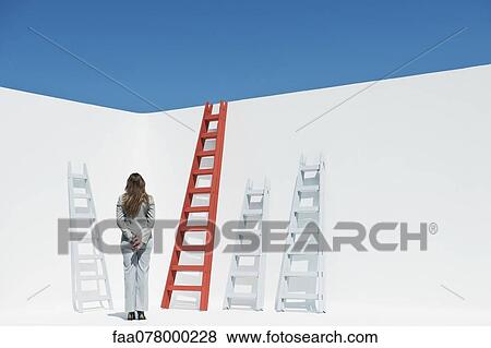 Stock Photo - Businesswoman contemplating ladders, rear view. Fotosearch
