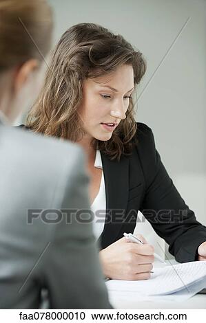 Stock Image - Businesswoman reviewing document. Fotosearch