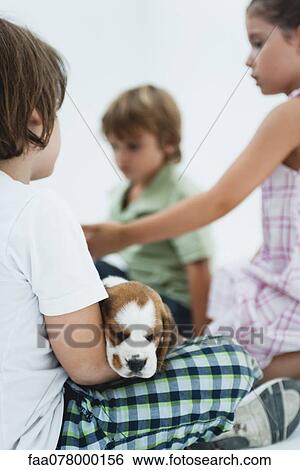Stock Photograph - Children hanging out, boy in foreground holding beagle puppy. Fotosearch