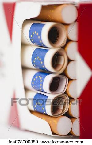 Stock Photo - Cigarette pack containing rolled euros. Fotosearch