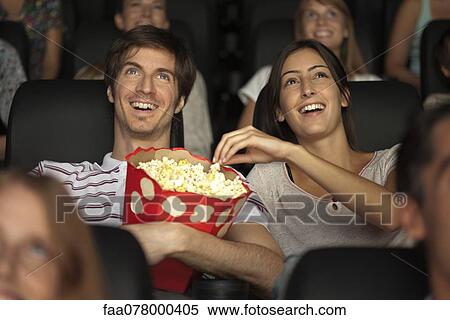 Couple eating popcorn in movie theater View Large Photo Image Stock Photography - Couple eating popcorn in movie theater. Fotosearch