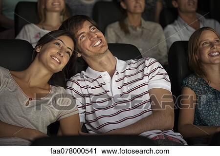 Stock Image - Couple enjoying movie in theater. Fotosearch