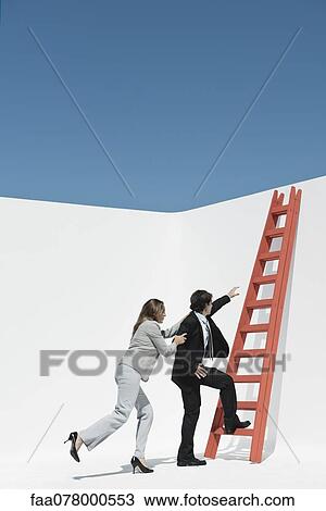 Stock Image - Executives racing each other to climb ladder. Fotosearch