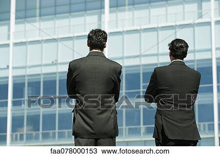 Stock Image - Executives standing in front of office building, rear view. Fotosearch
