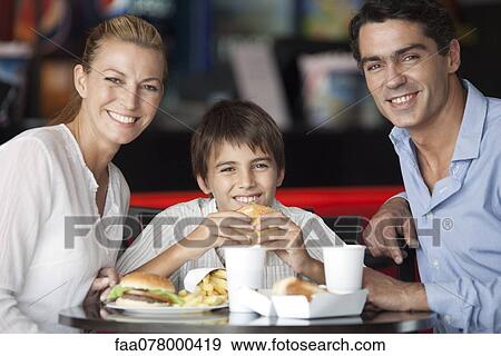 Family eating together in fast food restaurant, portrait View Large Photo Image Stock Photo - Family eating together in fast food restaurant, portrait. Fotosearch