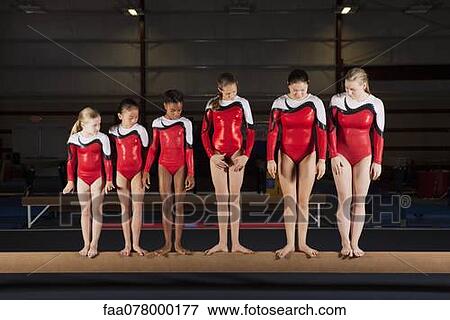 Stock Photo - Female gymnasts of various ages standing in a row on balance beam. Fotosearch