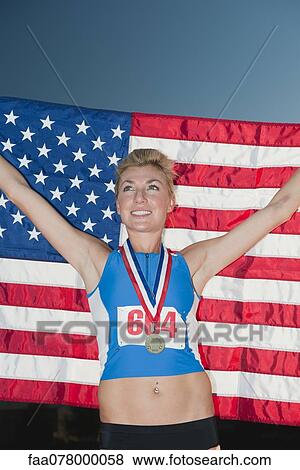 Stock Photo - Female medal winner holding up American flag in victory. Fotosearch