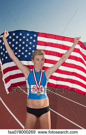 Stock Photo - Female medal winner holding up American flag in victory. Fotosearch