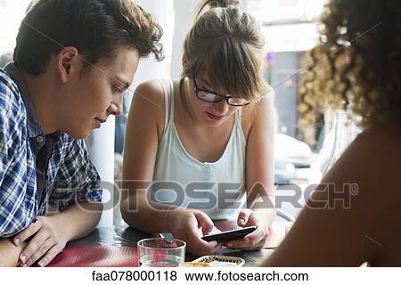 Friends hanging out in cafe, woman text messaging on cell phone View Large Photo Image Stock Photo - Friends hanging out in cafe, woman text messaging on cell phone. Fotosearch