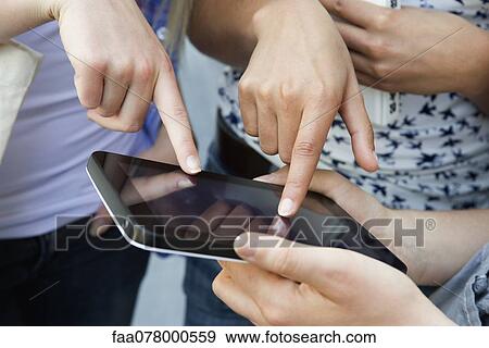 Stock Photo - Friends using digital tablet, cropped. Fotosearch