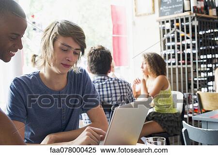 Stock Photography - Friends using laptop computer in cafe. Fotosearch