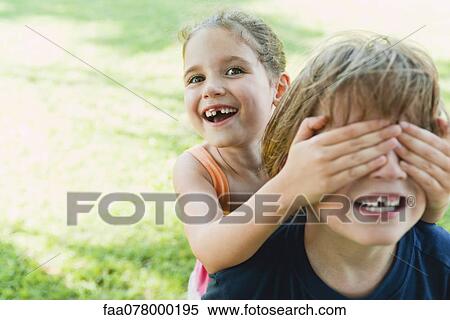 Stock Photography - Girl covering boy's eyes. Fotosearch