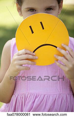 Girl hiding behind sad face mask View Large Photo Image Stock Image - Girl hiding behind sad face mask. Fotosearch